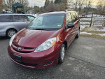 2010 Toyota Sienna LE in excellent condition with 7-passenger seating and alloy wheels in a driveway.