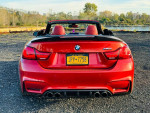 Red 2015 BMW M4 Convertible with 700+ horsepower, showing rear view and alloy wheels.