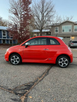 2014 red FIAT 500E parked on a street, showcasing its compact design and electric features