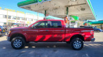 2011 Ford F-150 Lariat 4WD parked at a gas station, showcasing its polished red exterior and chrome wheels.