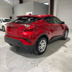 2020 Toyota C-HR LE Sport Utility in red, showcasing its sleek design and modern features, parked indoors.