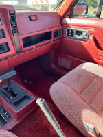 Interior of a classic Jeep Wagoneer with burgundy trim, featuring clean upholstery and dashboard.