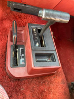 Interior view of a classic Jeep Wagoneer gear shift and 4-wheel drive controls on burgundy trim.