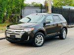 2013 Ford Edge SEL FWD in black parked on street with lush greenery in background, showcasing clean design and alloy wheels.