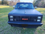 Front view of a rust-free 1987 GMC Jimmy Sierra Classic with satin black paint in a grassy area.