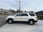 2010 GMC Acadia SLT in pearl white, showcasing its sleek design and spaciousness on a driveway.