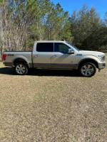 2018 Ford F-150 King Ranch Supercrew truck parked in a grassy area with trees in the background.
