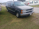 1999 Chevrolet Suburban parked on grass, featuring new tires and front lights, ideal for family trips.