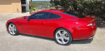 2014 Jaguar XKR Coupe in red, showcasing its sleek design and immaculate condition, parked outdoors.