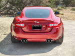 Rear view of a 2014 Jaguar XKR coupe in immaculate red condition with dual exhaust.