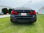 2017 BMW 540i xDrive M Sport with dual exhaust parked on grass, showcasing sleek rear design.