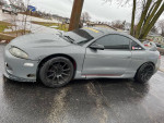 1995 Mitsubishi Eclipse GST with custom turbo and performance upgrades parked on wet pavement.