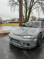 1995 Mitsubishi Eclipse GST with performance upgrades parked in a rainy area, showcasing its sporty design.