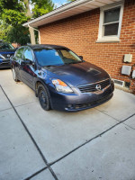 2009 Nissan Altima 2.5S in blue/gray color, showing exterior wear and parked on a driveway.