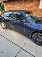 2009 Nissan Altima 2.5S with body damage, blue/gray color, parked on a driveway.