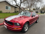2005 Ford Mustang Deluxe Coupe in red with clean exterior parked on a street, showcasing great condition and classic design.