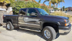 2003 Chevrolet Silverado 2500 HD LS 4x4 with chrome wheels and fog lights in a residential area