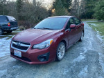 2012 Subaru Impreza Hatchback in red, showing minor scratches and dust on a gravel road.