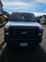 Front view of a well-maintained 2012 Ford E-250 work van parked on a residential street