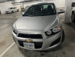 2015 Chevrolet Sonic LT FWD parked in a garage, showcasing its silver exterior and clean design.