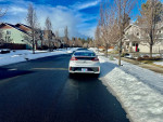 Rear view of a 2019 Hyundai Ioniq Electric parked on a snowy street with houses in the background.