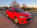 2018 Chevrolet Sonic LT in red with grey interior parked on the street, showcasing its sporty design and features.