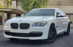 2013 BMW 740i RWD in white, showcasing its sporty design and luxury features, with low mileage of 64,000.