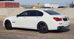2013 BMW 740i RWD in white, featuring a sleek design and black wheels, showcasing its elegant profile.