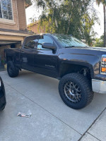 2015 Chevrolet Silverado 1500 LT 4WD with custom lift and new tires parked in driveway.