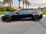2018 Tesla Model S P100D in black color parked on a street with palm trees in the background.