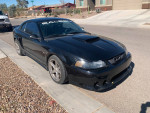 2001 Saleen Mustang in black with modified supercharged engine and cosmetic imperfections, parked on the street.