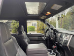 Interior view of a 2014 Ford F350 Super Duty 4x4 truck showcasing black leather seats and sunroof.
