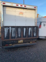 Rear view of a 2002 Ford E350 box truck with lift gate, showing worn paint and dual rear wheels.