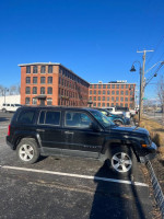 2012 Jeep Patriot parked near a historic brick building, showcasing its all-wheel drive and new parts.