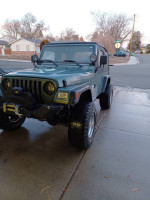 1999 Jeep Wrangler with 33-inch tires and upgraded suspension, parked on a driveway in Nevada.