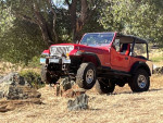 1994 Jeep Wrangler offroading on rocky terrain with lifted suspension and all-terrain tires.