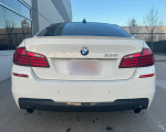 Rear view of a 2011 BMW 535xi M-sport sedan in Alpine white, showcasing its sleek design and BMW branding.