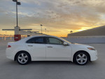 Side view of a 2010 Acura TSX in White Pearl color, parked with sunset backdrop, showcasing its clean and modern design.