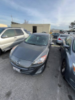 2010 Mazda 3 with clean title, needs transmission repair, parked among other vehicles