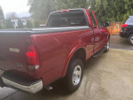 1999 Ford F-150 XLT 4WD in red, displaying its well-maintained exterior and new tires, parked on a driveway.