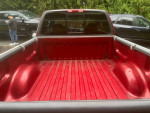 Red truck bed of a 1999 Ford F-150 XLT 4WD, well-maintained, showing clean interior and no damage.
