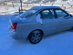 Side view of a 2002 Hyundai Elantra parked in snow, showcasing its manual transmission and good tire condition.
