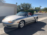 1997 Porsche Boxster convertible in silver with red leather interior, parked outside, showing no signs of wear.