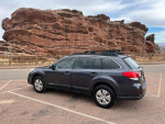 2013 Subaru Outback parked with mountains in background, showcasing its rugged design and adventure-ready spirit.