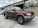 1999 Nissan Pathfinder XE RWD, a clean SUV with low mileage, parked outside a building.
