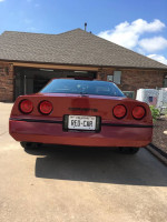Rear view of a classic 1987 Chevrolet Corvette parked in a driveway, showcasing its iconic design.