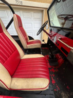 Interior view of a 1973 Jeep CJ5 showing red and beige seats and dashboard details.