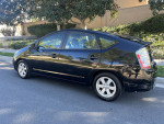 2008 Toyota Prius with leather seats and GPS parked on a residential street, showcasing its sleek black finish.