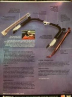 1985 Chevrolet Corvette with aftermarket side exhaust and various uninstalled parts, parked in a garage.