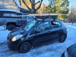 2007 Toyota Yaris hatchback parked on snow with roof rack, ideal for winter travel and reliable performance.